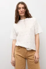 Remera blanca de manga corta con tejido de broderie, cuello redondo y diseño holgado.
