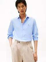 Camisa de manga larga para hombre, color celeste claro, con cuello con botones y corte slim. Presenta un pequeño logo bordado en el pecho.