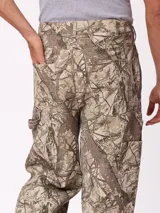 Pantalon recto de lona, color beige, con diseño de paneles reforzados en las piernas y cierre frontal con boton.