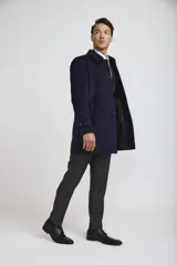 Abrigo tipo carcoat de corte clásico y estructura formal, en color azul marino. Presenta cierre frontal con botones, cuello camisero y bolsillos laterales. El interior cuenta con un forro oscuro con detalles en contraste.