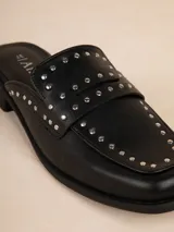Zuecos negros de símil cuero con tachas en la capellada, taco de 3cm y suela acolchonada.