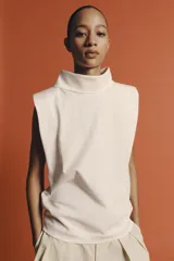 Top negro de hilatura de algodón, sin mangas y con cuello subido. Cuenta con cierre en la espalda mediante botones a presión.