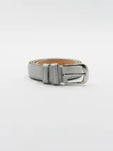 Cinto fino color plateado con hebilla metálica rectangular.