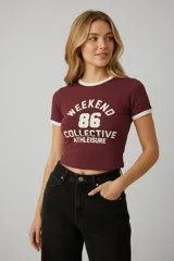 Remera de algodón con elastano, de corte ajustado y estilo ringer, con cuello y bordes de mangas en color crema. Presenta un estampado frontal con estilo universitario en color crema sobre fondo bordó.