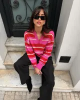Sweater de tejido de punto con diseño de rayas horizontales en tonos fucsia, rojo y blanco, con escote en V y cuello tipo polo.