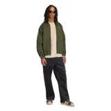 Campera Adidas modelo SST TT color verde militar, con cierre frontal, cuello alto y las clásicas tres tiras de la marca en las mangas. Cuenta con el logo del trifolio bordado en el pecho.
