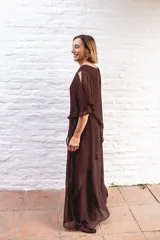 Vestido largo de gasa color bordó, con diseño de capas superpuestas y terminaciones en picos diagonales. Presenta mangas tipo capa que cubren sutilmente los brazos, brindando elegancia y libertad de movimiento.
