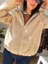 Campera con cuerpo de piel sintética tipo teddy y mangas acolchadas. Presenta cierre frontal, capucha y diseño de corte recto.