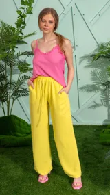 Pantalón de corte ancho y fluido en color amarillo, confeccionado en crepe. Presenta cintura elástica con cordón ajustable y bolsillos laterales.