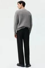 Pantalón de corte relajado color negro, con cintura elástica, cierre frontal con botón y cordón de ajuste oculto. Presenta piernas con raya marcada, bolsillos laterales al bies y bolsillos traseros ribeteados con botón.