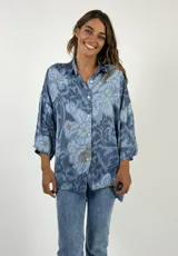 Camisa celeste con estampado floral en tonos azules y beige, de corte holgado y mangas 3/4.