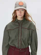 Camisa western de algodón grueso color verde militar, con corte holgado y aplicaciones de hilo en contraste en el pecho, la cartera de botones y los puños.
