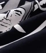 Remera deportiva de corte oversized, color negro, con estampado gráfico en la espalda del equipo Las Vegas Raiders de la NFL. Presenta cuello redondo, mangas cortas con detalles de rayas blancas y logo de la NFL en la parte superior trasera.