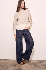 Sweater de punto con cuello alto, corte holgado y diseño color block en tonos beige y blanco.