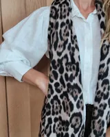Bufanda de gran tamaño con estampado animal print en tonos negro y beige, con terminación de flecos en los extremos.