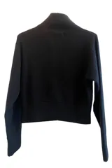 Saco negro de tejido de punto en mezcla de baby alpaca y lana, con cuello camisero, cierre frontal con cremallera con dije de perla, bolsillos frontales con solapa y botones decorativos.