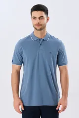 Remera polo de piqué azul marino, con cuello y puños de mangas cortas con ribete blanco en contraste, cierre frontal de dos botones y pequeño logo bordado en el pecho.