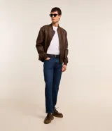 Pantalón de jean azul oscuro para hombre, con corte slim, diseño clásico de cinco bolsillos, trabillas para cinturón y cierre frontal con botón y cremallera.