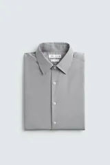 Camisa de corte slim fit confeccionada en tejido de algodón con textura. Presenta cuello italiano, manga larga con puños abotonados y cierre frontal de botones.