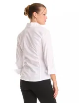 Camisa blanca entallada con cuello solapa y escote en V. Presenta un diseño frontal con tablitas horizontales, cierre central con botones y mangas tres cuartos con puños anchos rebatibles.