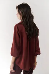 Camisa azul marino de satén con cuello clásico, cierre frontal con botones y mangas largas con puños abotonados.