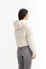 Campera puffer corta de color negro, con capucha, cierre frontal con cremallera y solapa con botones a presión.