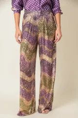 Pantalón italiano de corte palazzo, con cintura elastizada y forro de viscosa. Cubierto de lentejuelas con diseño de ondas en tonos violeta, dorado y verde.