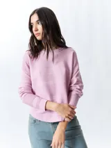 Mochila pequeña color rosa pálido con correas ajustables y asa superior. Tiene un bolsillo frontal con cierre y un parche con el logo de la marca en la parte inferior.