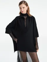Poncho tejido de punto color negro con escote en V y cuello tipo polo. Presenta un diseño holgado con mangas tres cuartos.