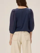 Blusa de diseño combinado con cuerpo delantero y espalda de algodón negro, y mangas abullonadas tres cuartos de lino en color beige con puños elásticos negros.