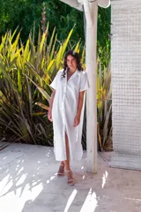 Vestido camisero de muselina color negro, de largo midi, con cuello clásico, manga corta y cierre frontal con botones.