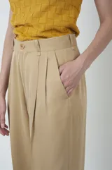 Pantalón de vestir color beige, de corte recto, con pinzas en la parte delantera y cierre con botón.