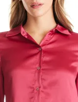 Camisa de satén color verde oliva, con cuello clásico, cierre frontal con botones metálicos y mangas largas con puños abotonados.