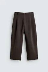 Pantalón de corte relajado color marrón oscuro, con pliegues frontales, cierre de cremallera y botón, bolsillos laterales y bolsillos traseros de vivo.