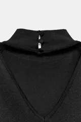 Top de punto negro sin mangas con cuello subido, hombreras y espalda descubierta.