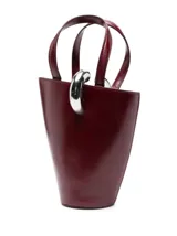 Bolso tipo cubo Jacquemus modelo Le Petit, confeccionado en cuero color bordó con acabado brillante. Cuenta con asas dobles superiores, correa bandolera extraíble, detalle de anilla metálica plateada en la parte frontal y el logotipo de la marca en letras metálicas.
