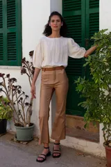 Pantalón de cuero sintético color marrón claro y marrón oscuro, de tiro medio/alto y silueta levemente acampanada desde la rodilla. Tiene bolsillos cuadrados y combina dos colores en frente y espalda.