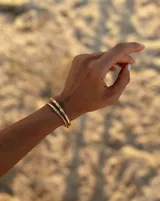 Brazalete rígido abierto de metal color plateado con textura irregular.