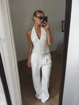 Top de cuello halter con escote profundo, confeccionado en tejido blanco con diseño de perforaciones circulares en toda la prenda.