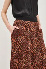 Falda larga de corte acampanado con estampado animal print de leopardo en tonos caramelo y negro. Presenta una cintura alta con detalle de banda decorativa con tachas metálicas.