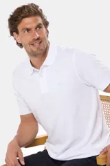 Remera polo de piqué color blanco, con cuello y puños en rib, cierre frontal con botones y logo bordado pequeño en el pecho.