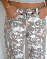 Pantalon de corte recto con estampado camuflado en tonos neutros, beige y marron. Presenta costuras verticales frontales que recorren el largo de las piernas, bolsillos laterales y cierre frontal con boton.