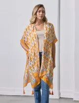 Kimono tejido con estampado abstracto en tonos azules, blancos y violetas. Tiene terminación de ruedo con borlas.