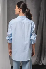 Camisa oversize de color celeste con un sutil diseño a rayas verticales blancas, manga larga y cuello camisero clásico.