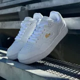 Championes Lacoste modelo Courtcage de diseño urbano, color blanco con detalles en dorado. Presentan el icónico logo del cocodrilo en el lateral y suela de goma resistente.