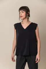 Blusa negra lisa con cuello en V y aplique de cruny en la espalda y en los hombros.