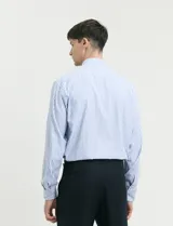 Camisa de manga larga con estampado de rayas verticales en azul y blanco, cuello clásico y bolsillo frontal.