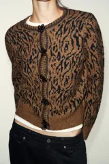 Chaqueta de punto con diseño jacquard de estampado animal en tonos marrón y negro. Presenta cuello redondo, manga larga y cierre frontal con botones decorados con abalorios.