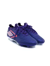 Championes de fútbol Umbro modelo Legacy HG, color violeta con detalles en coral y blanco. Presentan un diseño texturizado en la superficie, cordones al tono y suela con tapones para césped.