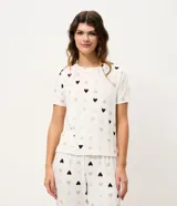 Blusa de pijama de manga corta con cuello redondo y corte regular, confeccionada en tejido peach touch con estampado de corazones pequeños en tonos neutros.